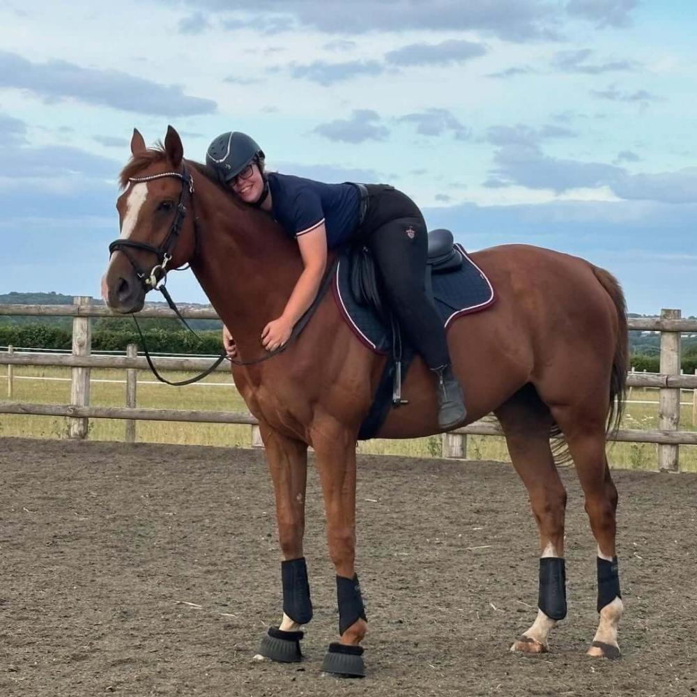 Young rider standing beside a pony fitted with a Cavaletti saddle pad in an outdoor riding area.