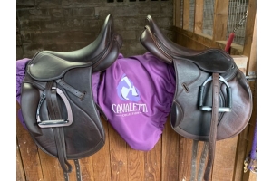 Two Cavaletti Collection saddles on a stable wall with a purple Cavaletti saddle cover in between — highlighting why saddle covers protect and extend the life of your tack.