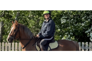 Rider sitting on a light brown horse with a bridle and light saddle pad in a quiet outdoor setting, Cavaletti Collection. Photo credit: jaffas.adventures.