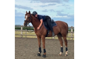 Young rider standing beside a pony fitted with a Cavaletti saddle pad in an outdoor riding area.