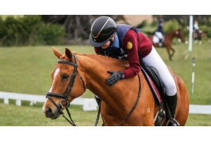 Rider in competition attire leaning forward to hug a chestnut horse during a dressage or show event showing a calm and positive connection between horse and rider. Image credit to olivia__equestrian