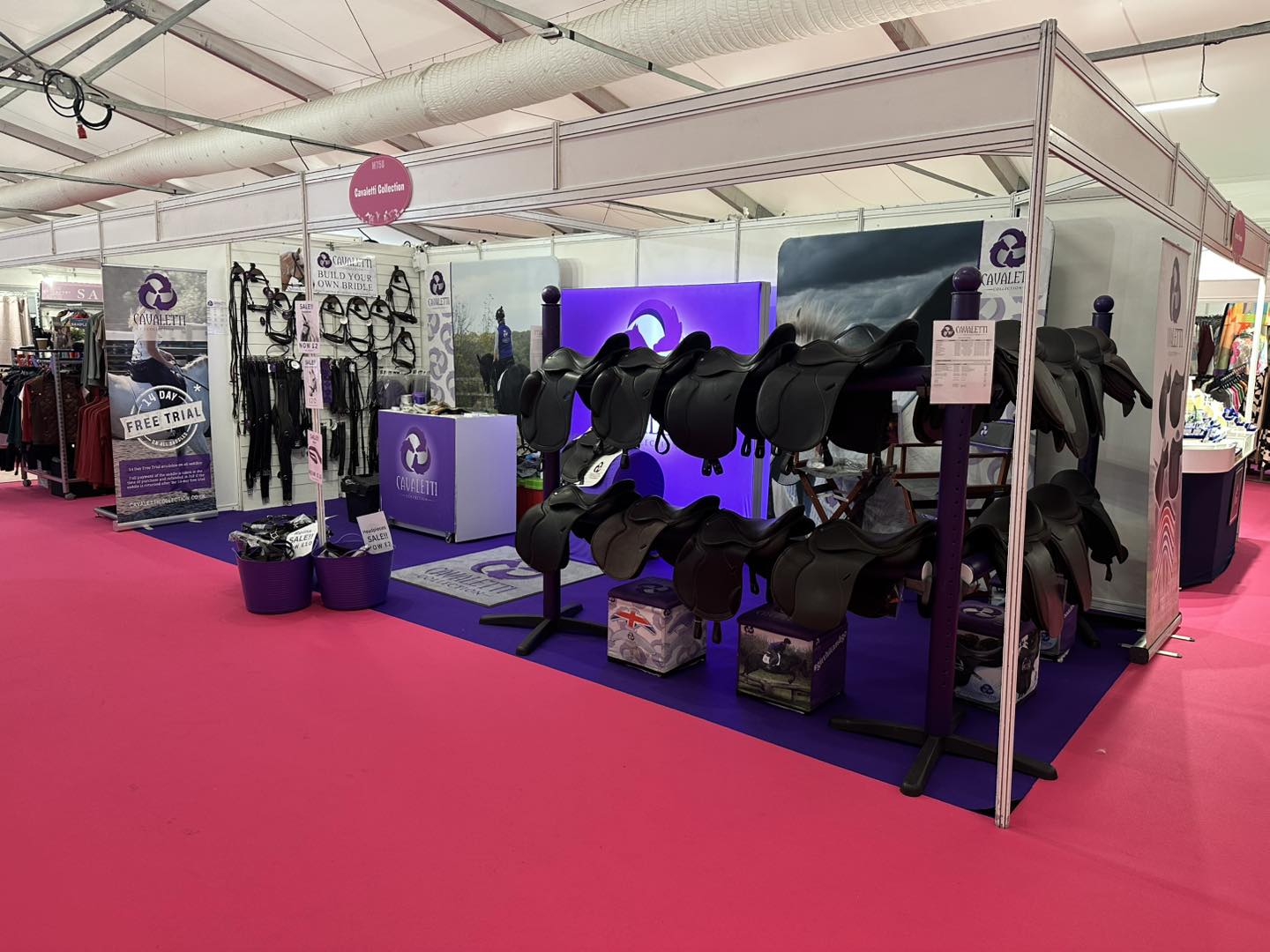 Cavaletti Collection trade stand displaying black saddles, bridles, and branded signage at an equestrian event.